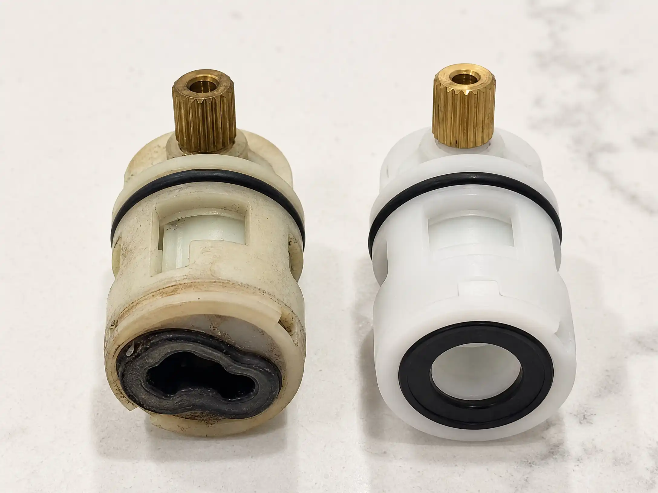Old faucet cartridge with a warped and cracked rubber seal next to a new replacement cartridge